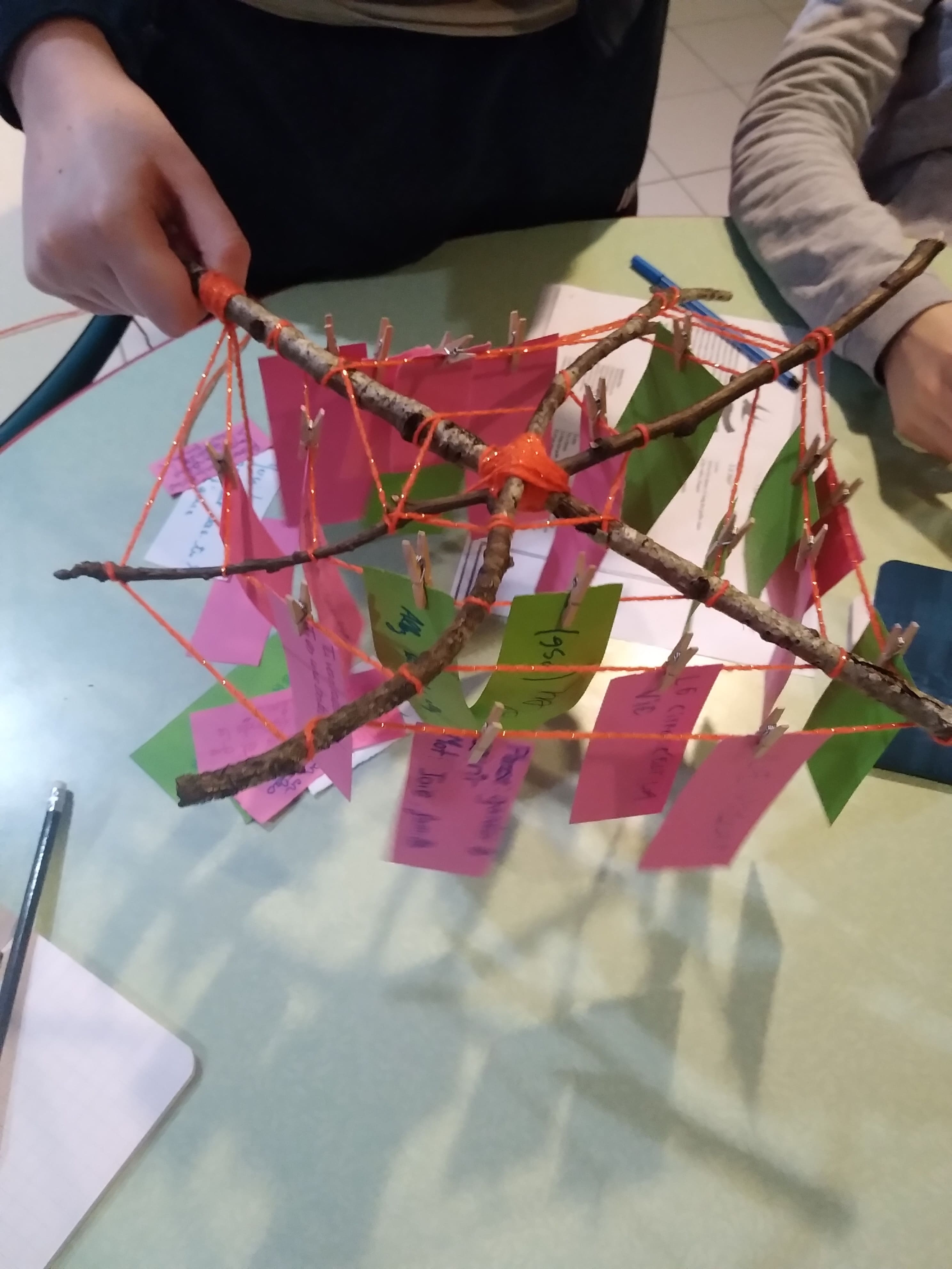 mobile en bois et laine qui tient des bout de papier avec des pinces